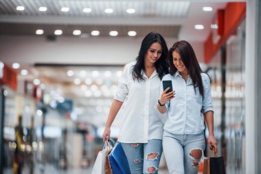 Telefonla. İki genç kadın süpermarkette alışveriş yapıyorlar..