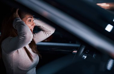 Yepyeni modern bir otomobilin içinde hareket eden genç bir kadının yan görüntüsü..