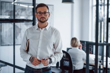 Ofiste duran resmi kıyafetler içindeki genç işadamının portresi..