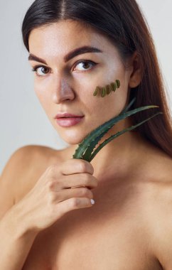 Çıplak kadın stüdyoda beyaz arka plana karşı aloe vera ile birlikte..