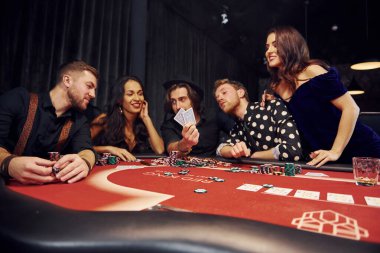 Kumarhanede birlikte poker oynayan bir grup zarif genç..