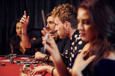 Bir bardak içkiyle. Kumarhanede birlikte poker oynayan bir grup zarif genç..
