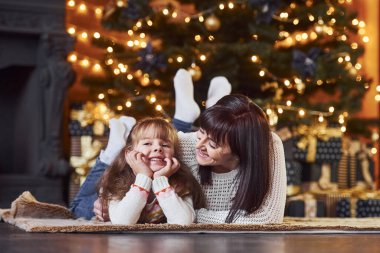 Küçük kız ve annesi Noel süslemeli odada yerde birlikte yatıyorlardı..