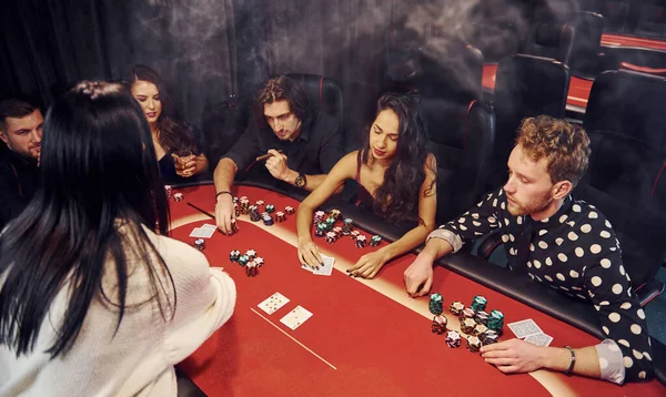 Kumarhanede birlikte poker oynayan bir grup zarif genç..