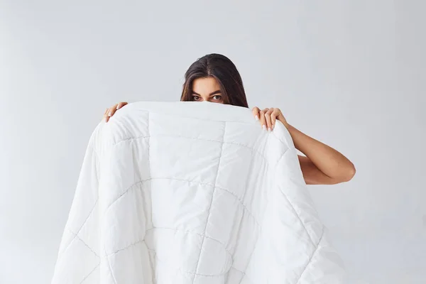 白い背景を背景にスタジオのタオルの後ろに隠れている女性 — ストック写真