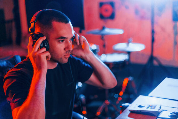 Sound engineer in headphones working and mixing music indoors in the studio.