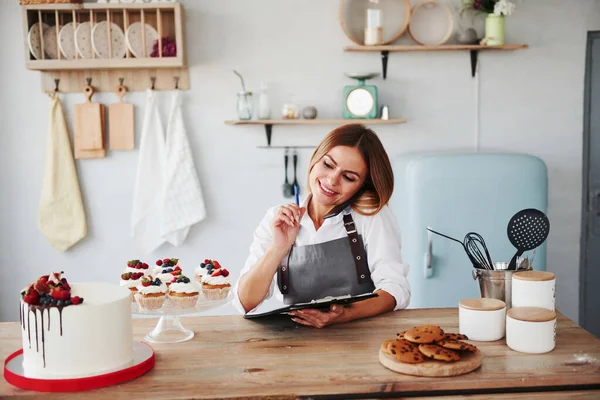 Bionda Prende Ordine Telefono Biscotti Fatti Casa Torta Sul Tavolo — Foto Stock