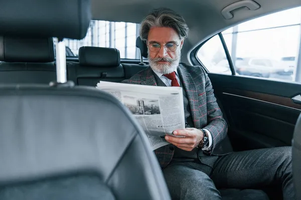 Nowoczesny Stylowy Starszy Pan Siwymi Włosami Wąsami Czytający Gazetę Samochodzie — Zdjęcie stockowe