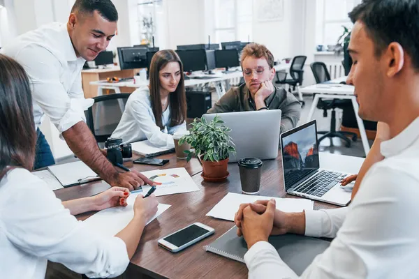 Ofiste yeni bir proje üzerinde çalışan konsantre bir grup insan.