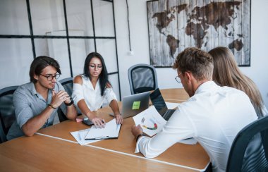 Masada ve ellerde bazı belgeler var. Ofiste çalışan resmi kıyafetli genç iş adamları..