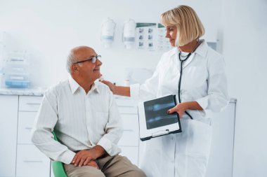 Kıdemli adamın klinikte kadın doktorun muayenesi var..