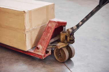 Üzerinde karton kutu olan kirli kırmızı palet kamyonunu kapat..