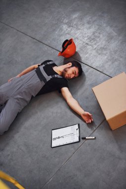 Depodaki bir kazadan sonra depo çalışanı. Üniformalı bir adam yerde yatıyor..