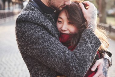 Kırmızı ekose kullanarak ısınıyorum. Şehrin dışında mutlu, çok ırklı bir çift. Kafkas sevgilisiyle Asyalı bir kız..