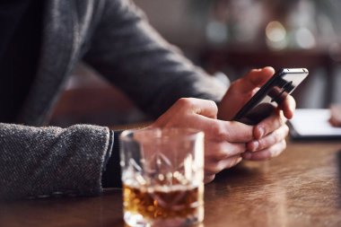 Kafede elinde telefonla oturan ve masada içki içen resmi giysili adama yakından bakın..