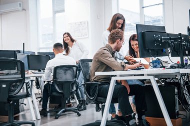 Modern ofiste bilgisayarla çalışan bir grup genç iş adamı..