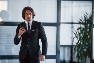 - Telefonu kullanarak. Siyah takım elbiseli ve kravatlı yakışıklı iş adamının portresi..