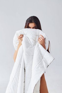 Stüdyoda beyaz arka planda havlunun arkasına saklanan kadın..