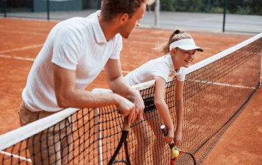 İnternete yaslanarak ara veriyorum. Spor üniformalı iki kişi kortta birlikte tenis oynuyor..