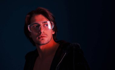 Güzel, uzun saçlı, gözlüklü seksi adam stüdyoda mavi ışıklı..