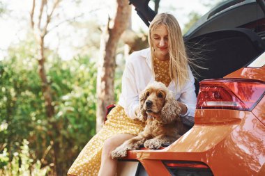Arabanın arka koltuğunda oturuyor. Köpeğiyle birlikte ormanda güzel vakit geçiren bir kadın..