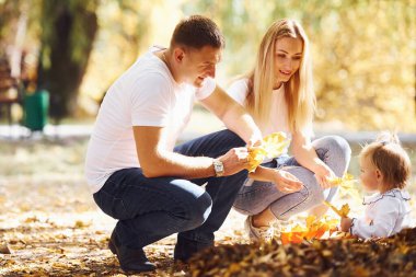 Neşeli genç aile birlikte bir sonbahar parkında dinleniyor..