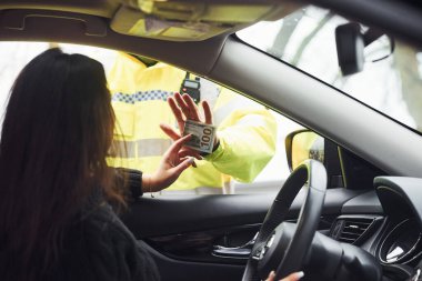 Yeşil üniformalı erkek polis memuru araçtaki kadından rüşvet almayı reddediyor..