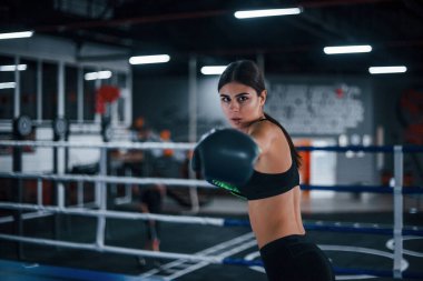 Spor kıyafetli genç bir kadın boks ringinde egzersiz yapıyor..