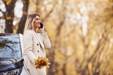 Arabanın yanında duran bir kız arıyor. Ormanda yepyeni bir otomobil..