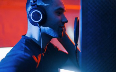 Vokalist, modern profesyonel stüdyoda kapalı bir yerde kayıt yapıyor..