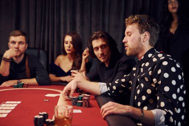 Kumarhanede poker oynayan bir grup zarif gencin yan görüntüsü..