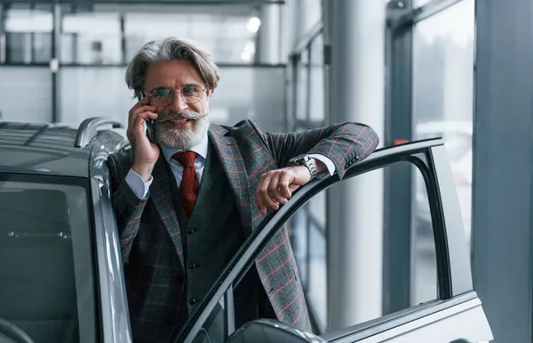 Starszy Biznesmen Garniturze Krawacie Siwymi Włosami Brodą Stojący Wewnątrz Telefonem — Zdjęcie stockowe