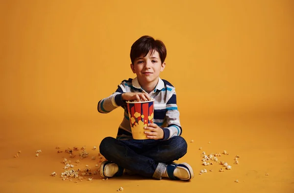 Roztomilý Chlapeček Sedí Dívá Film Popcorn Proti Žluté Zdi — Stock fotografie