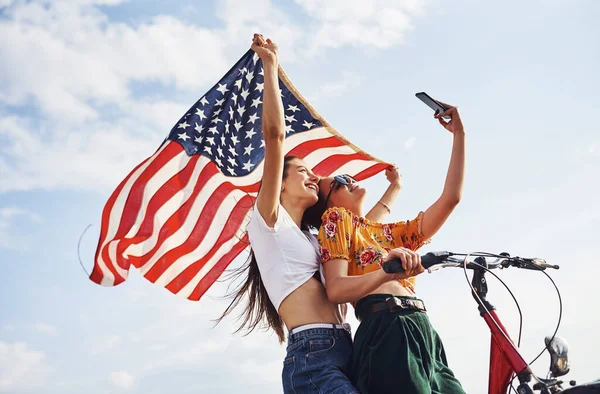 两个手拿着自行车和美国国旗的爱国快乐的女人自私自利 — 图库照片