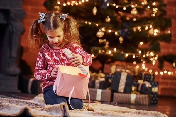 かわいいです女の子座っていますザ装飾されたクリスマスルームオープニングギフトボックス — ストック写真