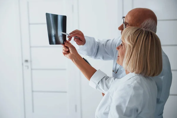 Beyaz Üniformalı Kıdemli Erkek Kadın Doktorlar Insan Bacağının Röntgenini Inceliyor — Stok fotoğraf