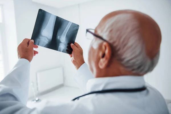 Hombre Mayor Médico Uniforme Blanco Examina Radiografía Piernas Humanas — Foto de Stock