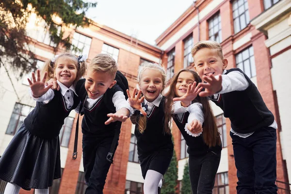 玩得开心 互相拥抱 一群穿着校服的孩子在教育大楼附近一起外出 — 图库照片
