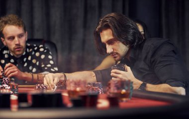 Bir bardak içkiyle. Kumarhanede birlikte poker oynayan bir grup zarif genç..