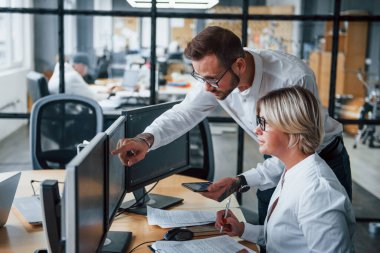 Bilgiyi birlikte analiz ediyoruz. Resmi giyinmiş iki borsacı ofiste finans piyasası ile birlikte çalışıyor..