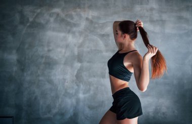 Zayıf vücutlu ve siyah spor elbiseli genç fitness kadını spor salonunda..