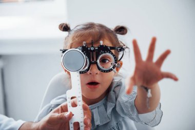 Göz hekimliği kliniğindeki küçük kız görme testi yaptırıyor..
