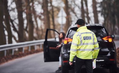 Yeşil üniformalı erkek polis yolda araca doğru yürüyor..