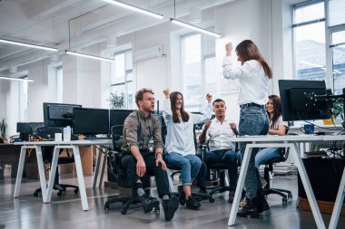 Bilgisayarların yanındaki modern ofiste insanlar konuşuyor ve birlikte çalışıyorlar..