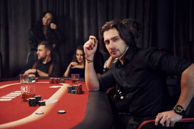 Kumarhanede birlikte poker oynayan bir grup zarif genç..