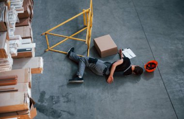 Depodaki bir kazadan sonra depo çalışanı. Üniformalı bir adam yerde yatıyor..