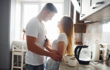 Sabahları genç bir çift modern mutfağın üzerinde birlikte duruyorlar..