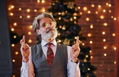 Gri saçlı, sakallı, ceketli ve beyaz gömlekli son sınıf öğrencisinin portresi süslü Noel odasında..