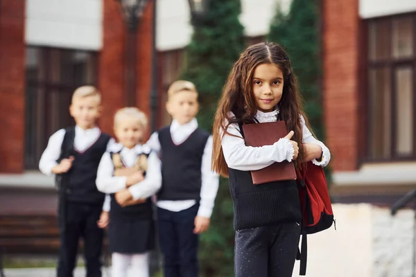 学校の制服を着た子供たちのグループが教育棟の近くで屋外で一緒にカメラをポーズ — ストック写真