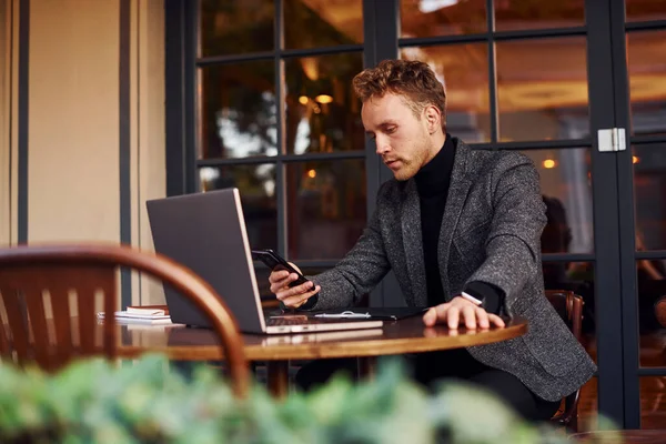 Resmi Kıyafetli Zarif Bir Genç Kafeteryada Dizüstü Bilgisayarıyla Oturuyor — Stok fotoğraf